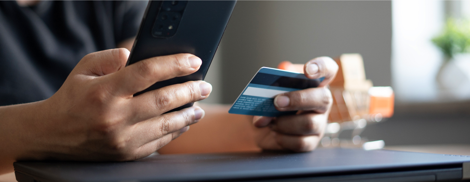 A person holding their card and mobile to make a payment