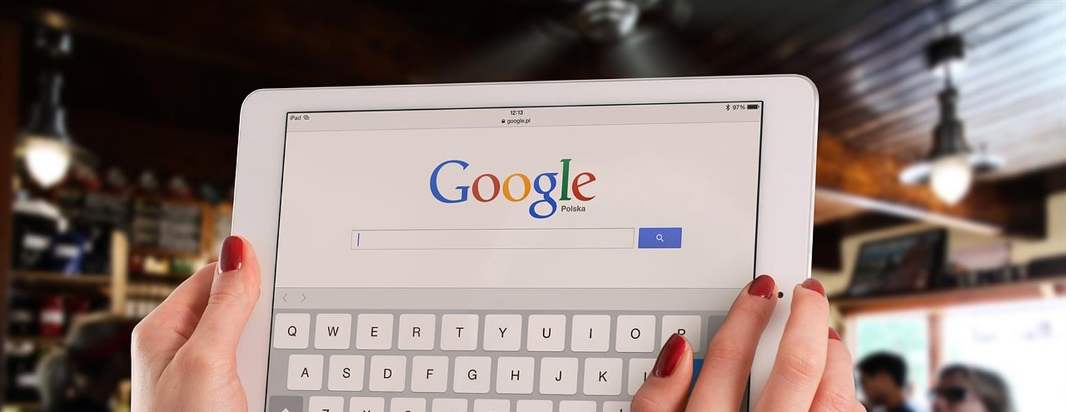 Person holding up a tablet with Google search page pulled up