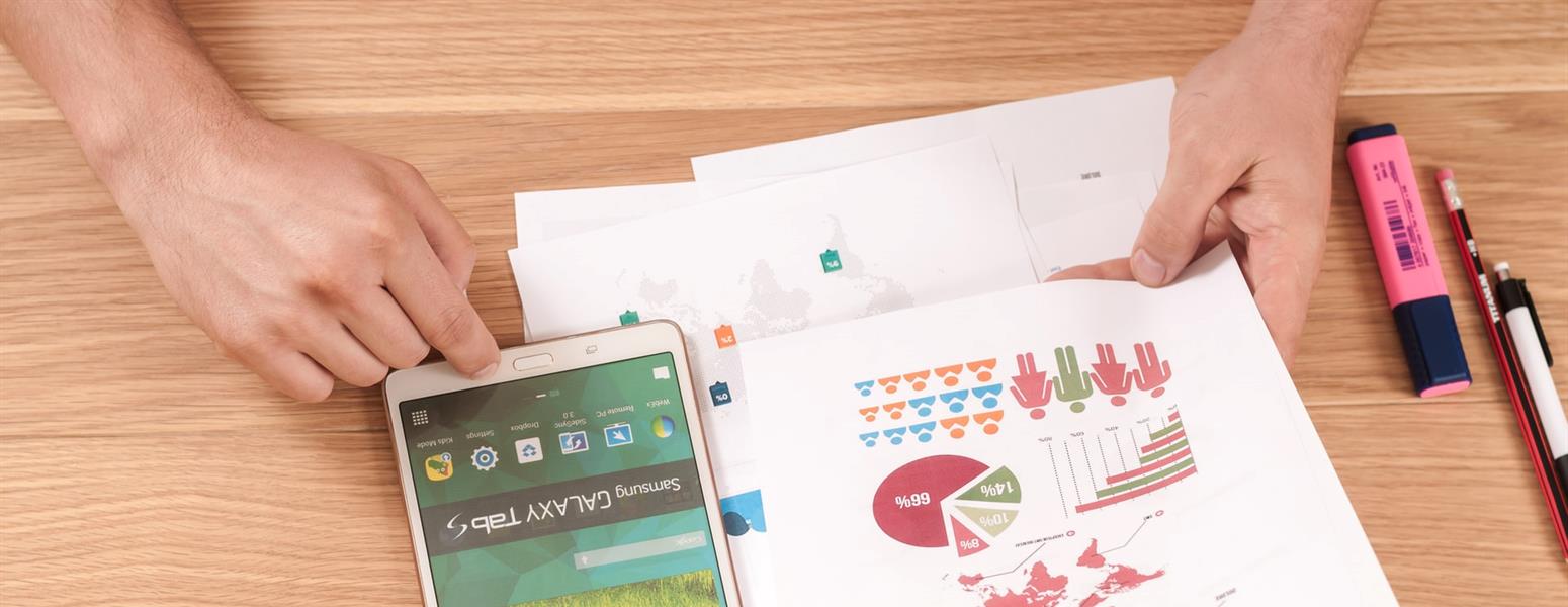 Person pouring over graphs and using a smartphone for research.