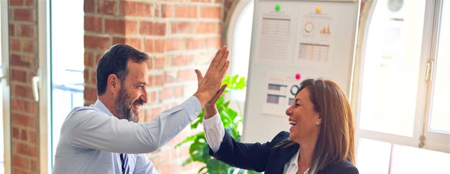 Two business people high five in an office setting