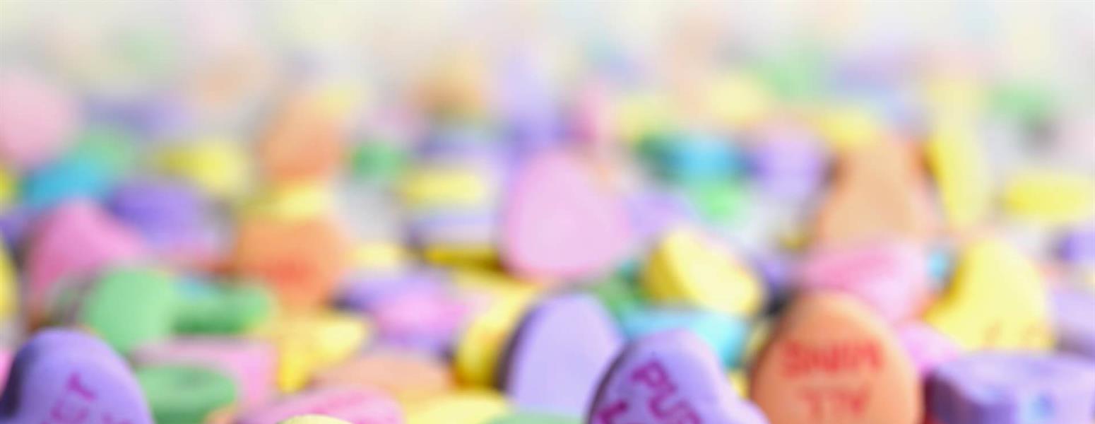 A pile of candy hearts with various messages of love