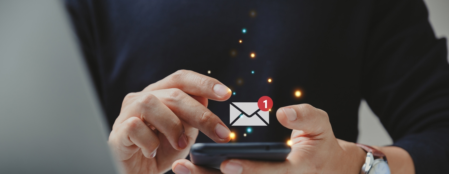 A man using a mobile phone with an email icon floating above it