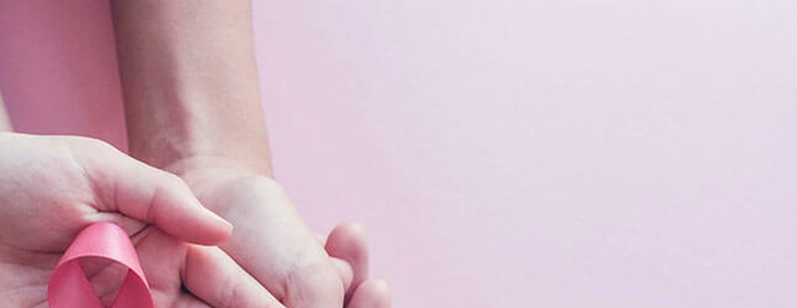 hands holding a pink cancer ribbon