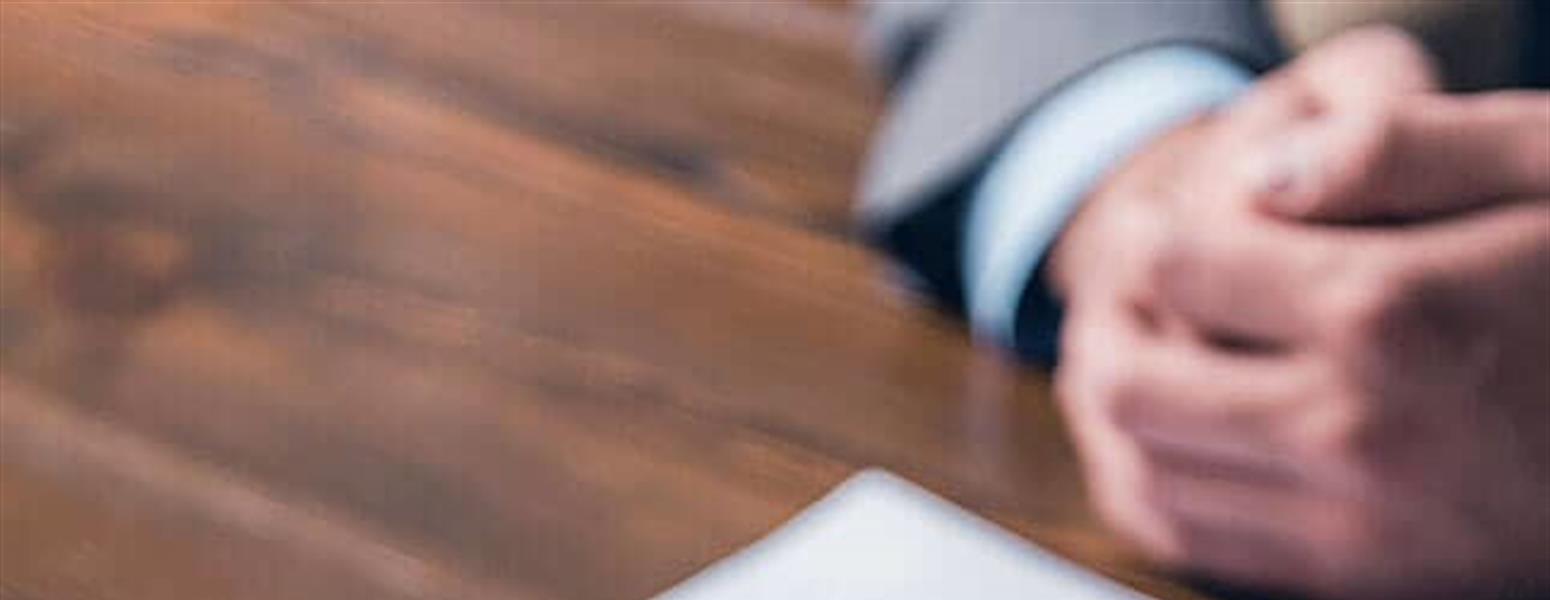 People sitting at a table with paperwork, a pen, and a ring