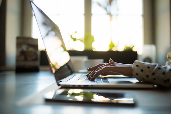 Woman types at a laptop.