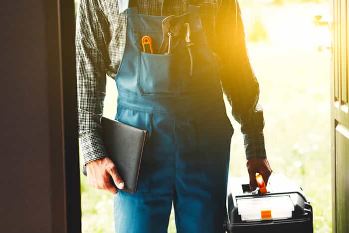 Plumber standing at door holding his tool box