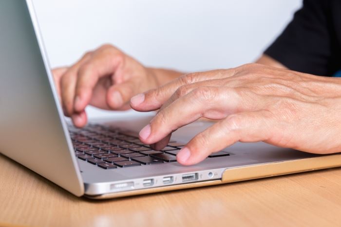 close-up of man typing on laptop