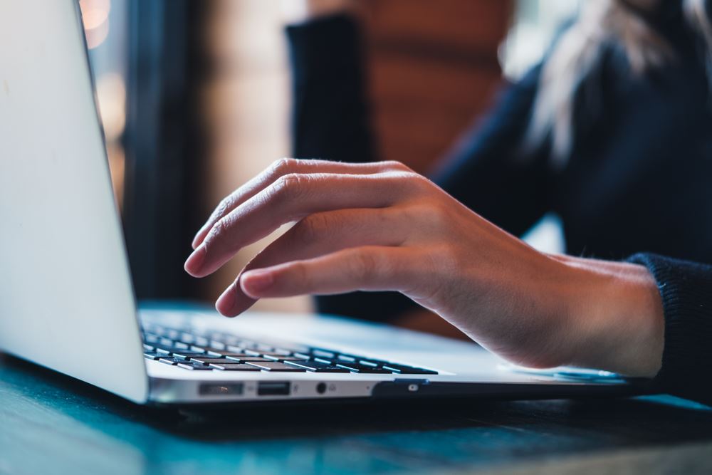 close-up of woman typing on a laptop